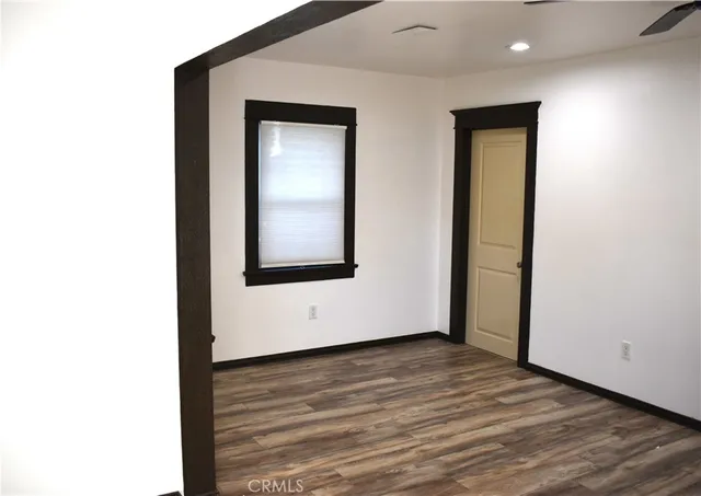 a view of an empty room with wooden floor and closet