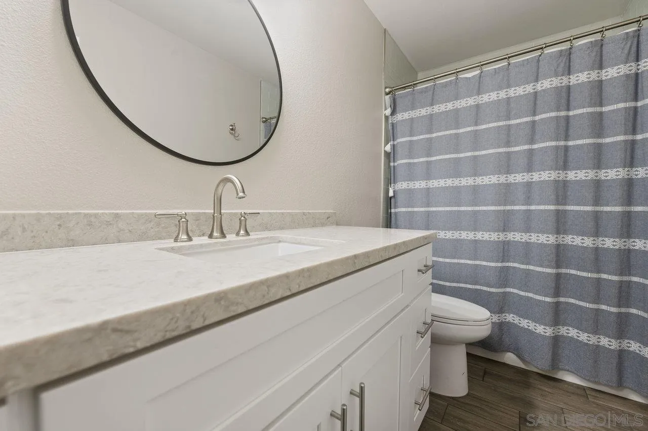 607 Maybritt Circle San Marcos, CA 92069 - Photo 27 of 38 a bathroom with a granite countertop sink a toilet and a mirror