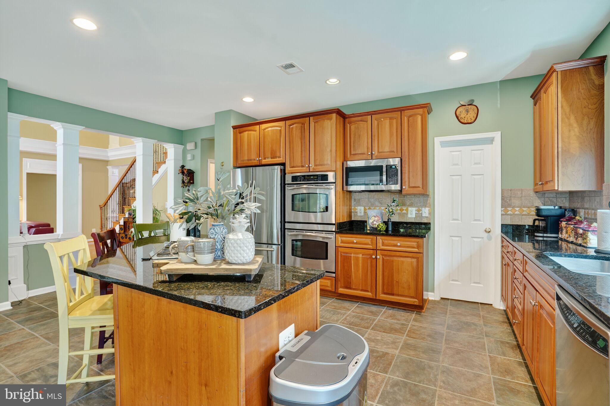 8157 American Holly Road Lorton, VA 22079 - Photo 17 of 48 a kitchen with stainless steel appliances granite countertop a stove top oven a sink dishwasher a dining table and chairs with wooden floor