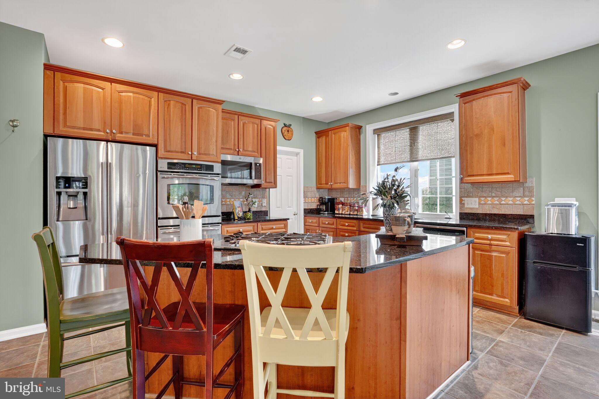 8157 American Holly Road Lorton, VA 22079 - Photo 18 of 48 a kitchen with stainless steel appliances granite countertop a stove a refrigerator a kitchen island a table and chairs