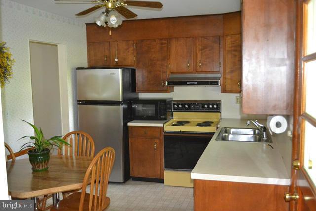 1209 Random Ridge Road Westminster, MD 21157 - Photo 8 of 12 a kitchen with stainless steel appliances granite countertop a refrigerator a stove a sink a dining table and chairs with wooden floor