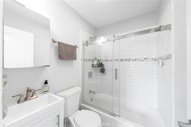 a bathroom with a shower sink vanity mirror and toilet