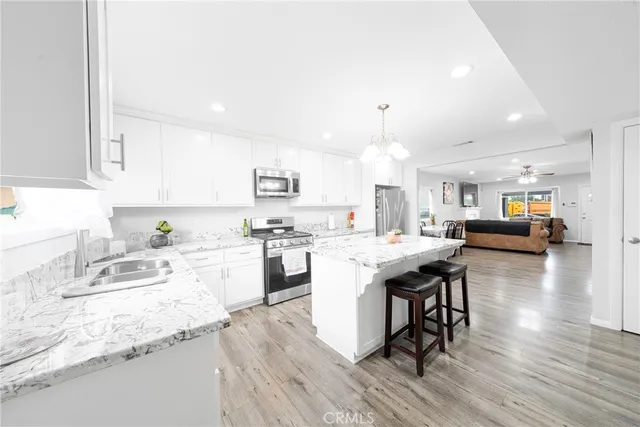 a kitchen with stainless steel appliances granite countertop a stove top oven a sink dishwasher and white cabinets with wooden floor