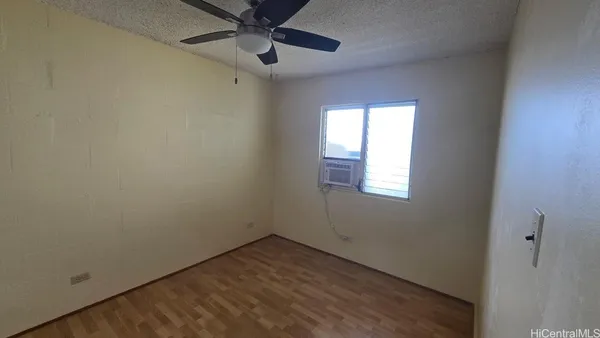 an empty room with a window and a fan