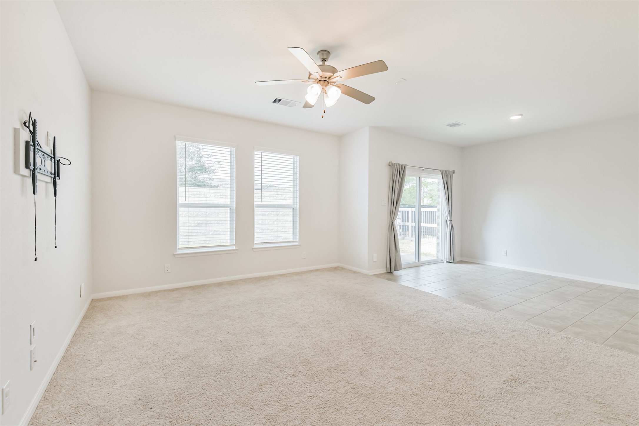 2129 Solstice Boulevard Spring, TX 77386 - Photo 20 of 49 Bright and open living room with large windows that bring in plenty of natural light. Neutral carpet and paint create a clean, welcoming feel. The room flows seamlessly into the dining area with tile flooring and easy access to the backyard through sliding glass doors.