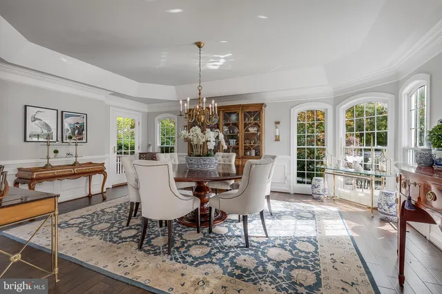 a kitchen with stainless steel appliances granite countertop a stove top oven a sink dishwasher a dining table and chairs with wooden floor