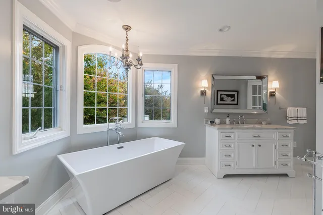 a view of a white house next to a yard with potted plants