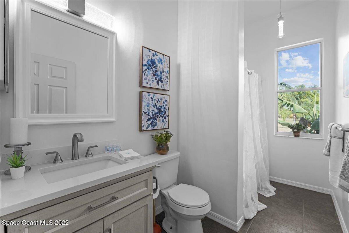 2030 Weber Road Malabar, FL 32950 - Photo 18 of 41 a bathroom with a granite countertop sink mirror vanity and toilet