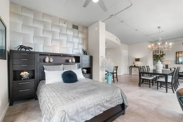 a bedroom with a bed and a lamp on dresser and a chandelier