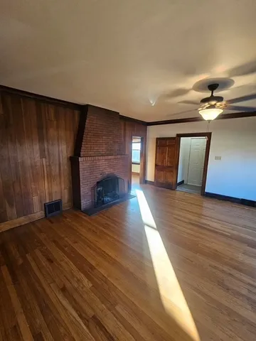 a view of empty room with wooden floor and fireplace