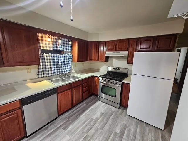 a kitchen with granite countertop a refrigerator stove and sink