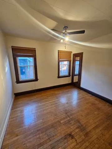 a view of an empty room with window and wooden floor