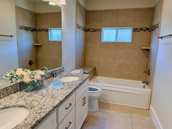 a bathroom with a granite countertop sink a toilet and shower