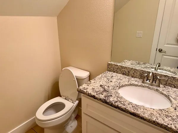 a bathroom with a granite countertop toilet a sink and a mirror
