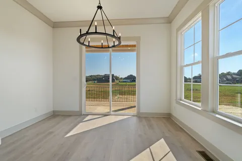 an empty room with wooden floor chandelier and windows