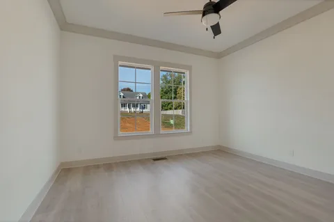 an empty room with ceiling fan and windows