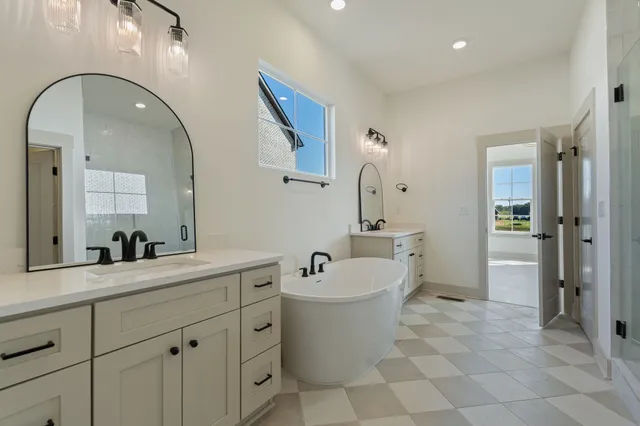 a spacious bathroom with a double vanity sink mirror and bathtub