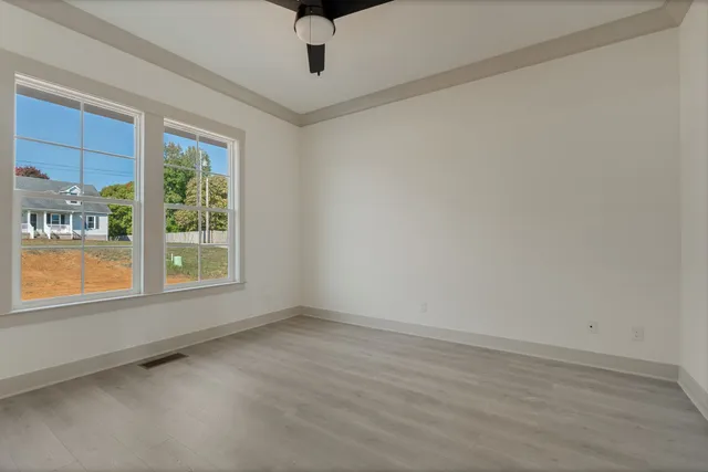 a view of an empty room with a window and wooden floor