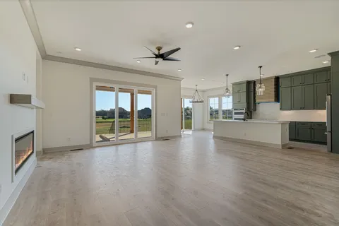 a view of an empty room with a kitchen and a window