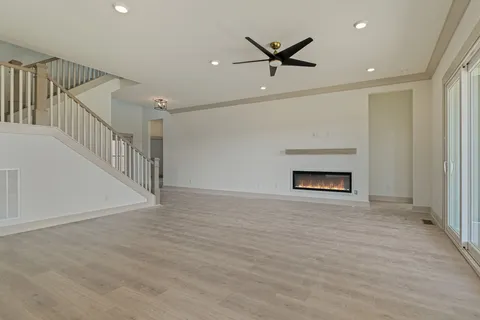 a view of an empty room with wooden floor fireplace and a window