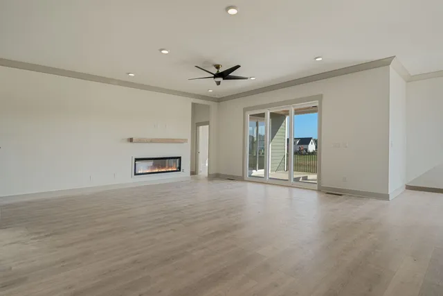 an empty room with chandelier fan and windows