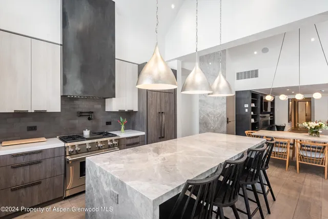 a kitchen with stainless steel appliances kitchen island a table chairs in it and wooden floors