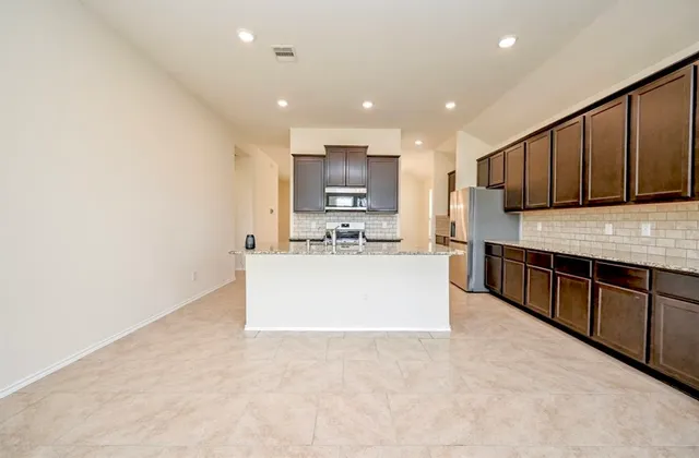 a large kitchen with stainless steel appliances granite countertop a stove a sink a refrigerator white cabinets and a oven