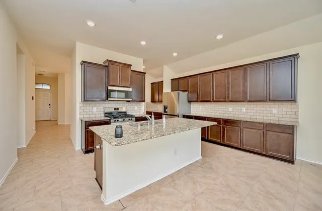 a kitchen with stainless steel appliances granite countertop a sink refrigerator and cabinets