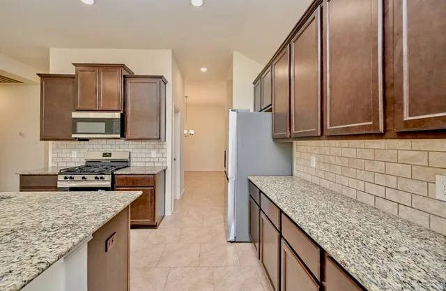 a kitchen with stainless steel appliances granite countertop a sink stove and refrigerator