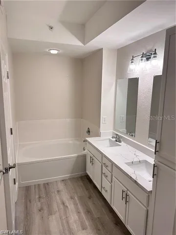 a spacious bathroom with a double vanity sink a mirror and a bathtub