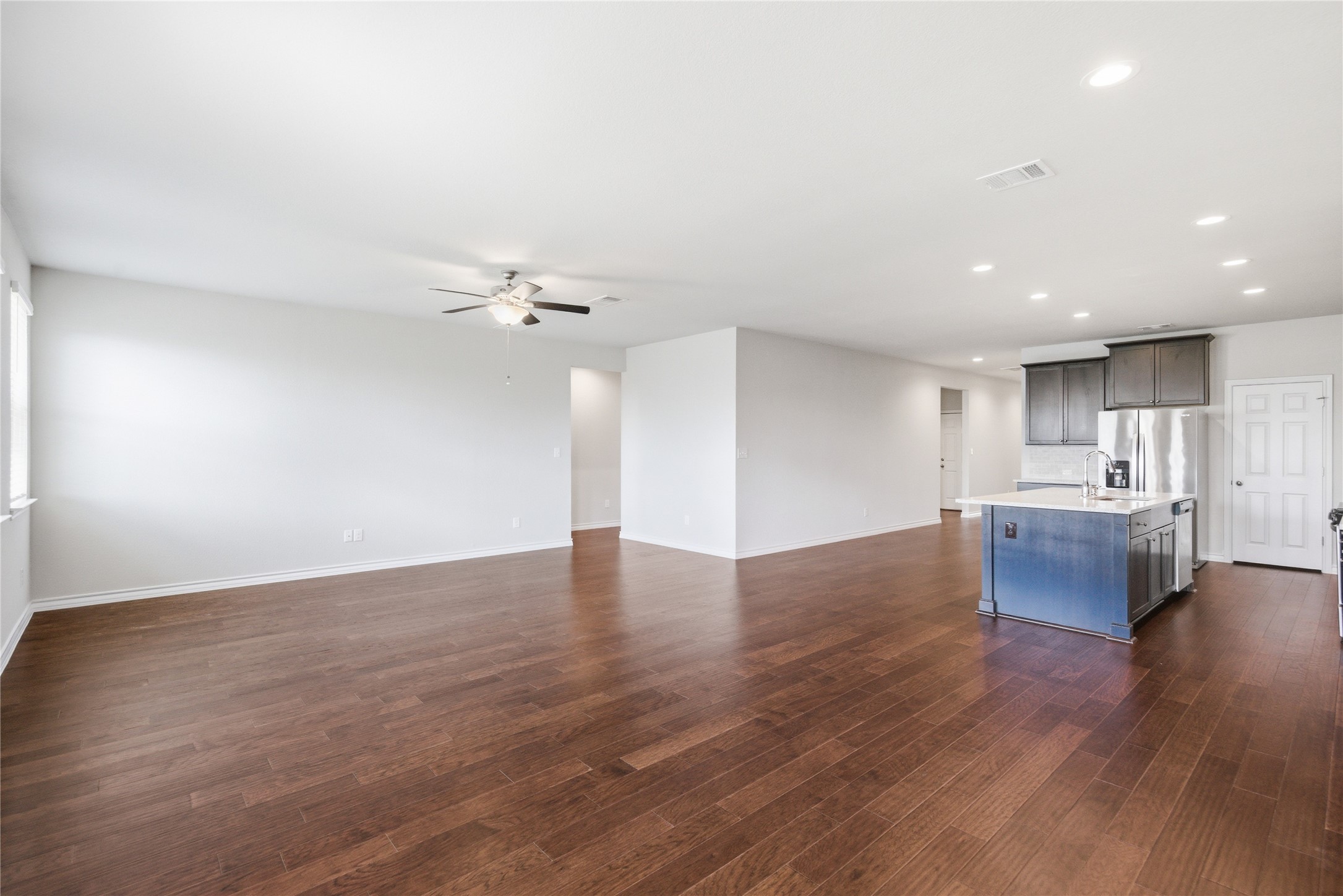 6764 Catania Loop Round Rock, TX 78665 - Photo 17 of 33 a view of an empty room with wooden floor and a kitchen