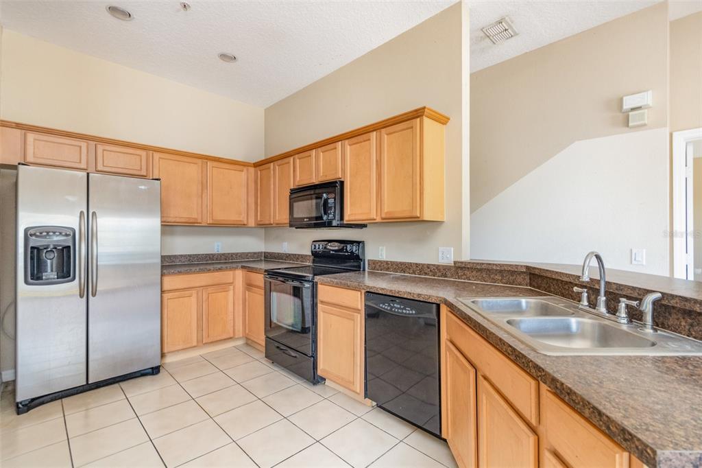 6686 South Goldenrod Road, Unit 139A Orlando, FL 32822 - Photo 12 of 23 a kitchen with stainless steel appliances granite countertop a sink stove microwave and refrigerator