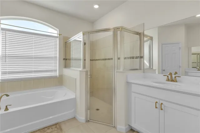 a bathroom with a bathtub a sink a vanity and a large mirror