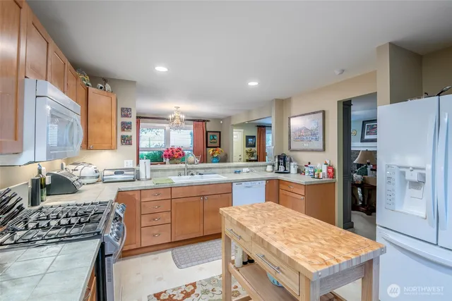 a kitchen with granite countertop a sink stove refrigerator and cabinets