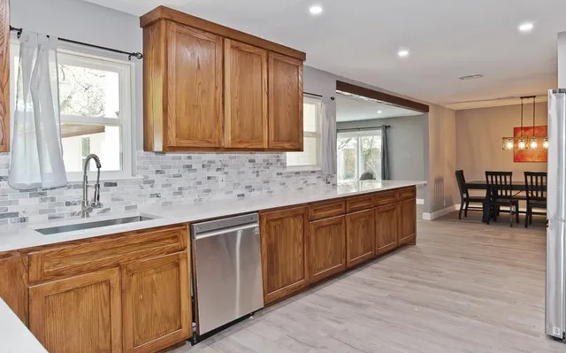 a large kitchen with kitchen island granite countertop a large window and white cabinets