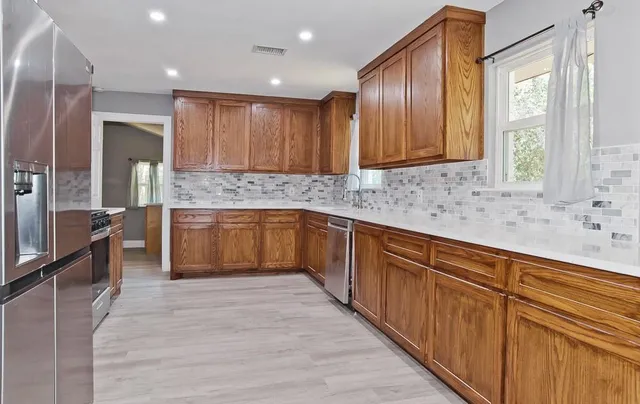 a kitchen with stainless steel appliances granite countertop wooden cabinets a sink and a large window