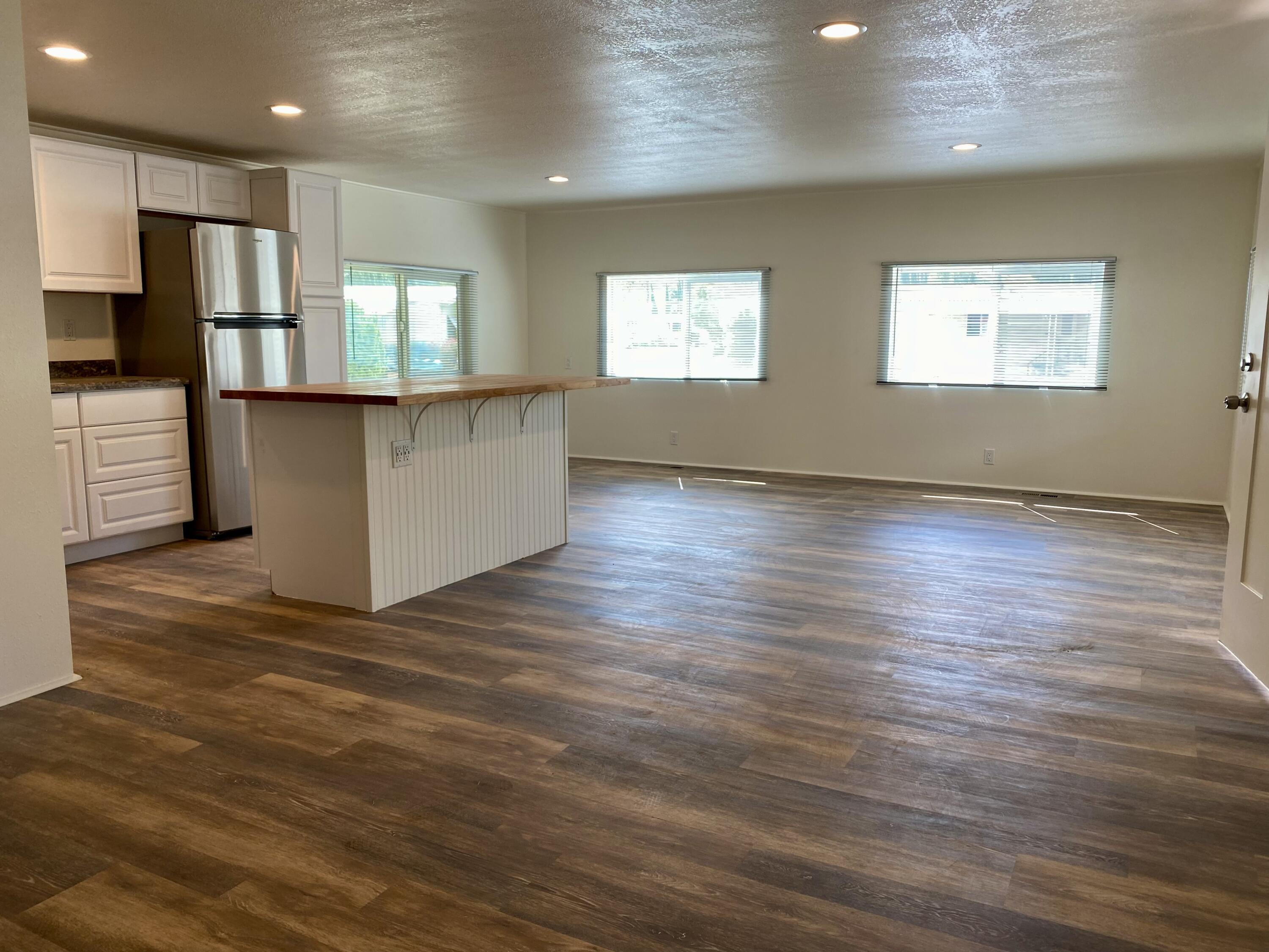 6480 Katherine Road, Unit 6 Simi Valley, CA 93063 - Photo 8 of 13 an empty room with wooden floor kitchen view and windows