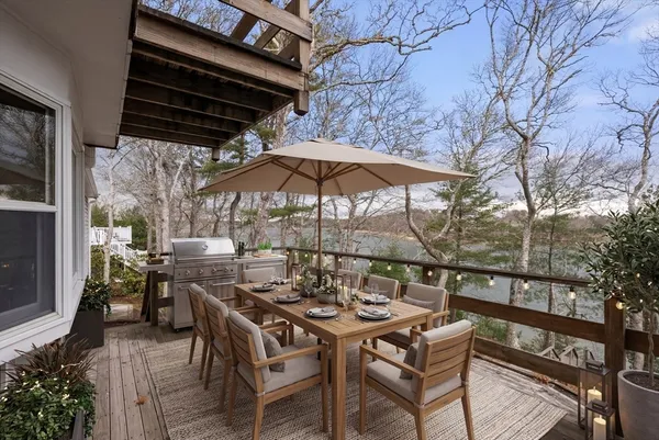 a view of a patio with table and chairs under an umbrella with a barbeque