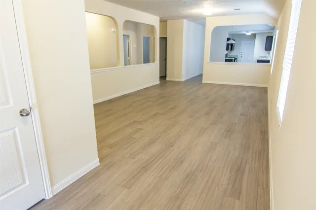 a view of a hallway with wooden floor and a bathroom