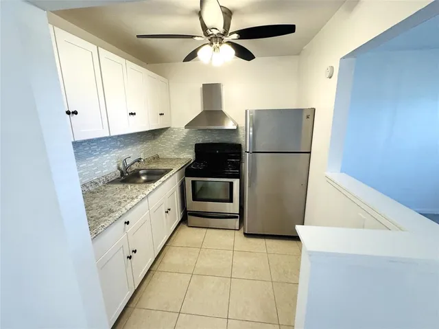 a kitchen with granite countertop a refrigerator a stove a microwave and white cabinets