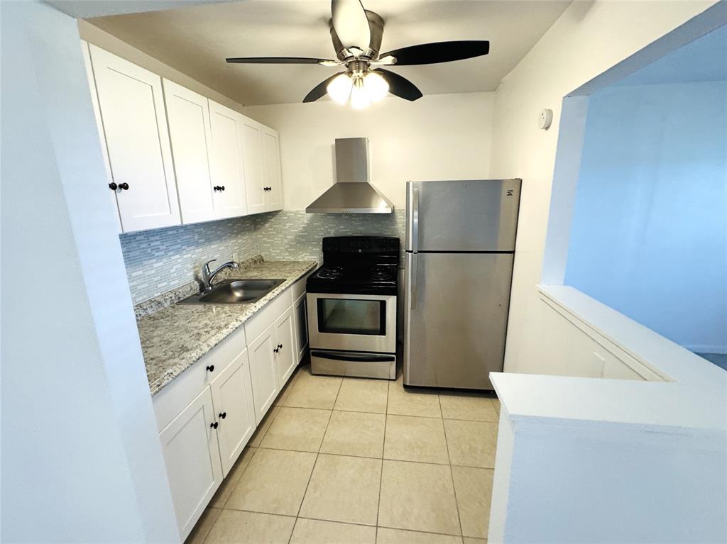 138 Fanshaw D, Unit D Boca Raton, FL 33434 - Photo 2 of 22 a kitchen with granite countertop a refrigerator a stove a microwave and white cabinets