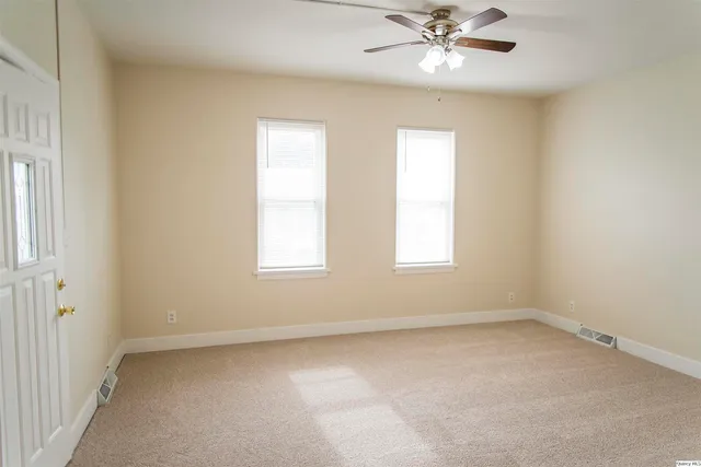 an empty room with a window and a fan