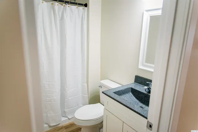 a bathroom with a granite countertop toilet and a sink