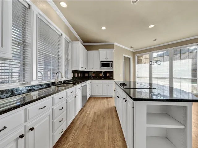 a large kitchen with granite countertop a large window and white cabinets