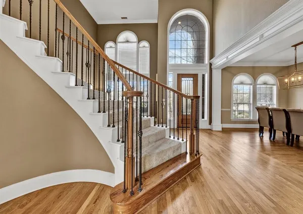 a view of staircase with two couches and a large window with wooden floor