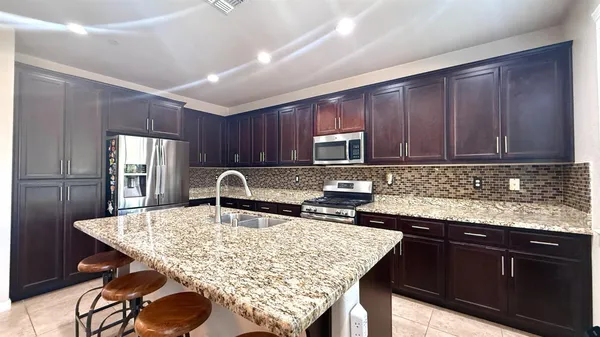 a kitchen with kitchen island granite countertop wooden cabinets a sink and appliances