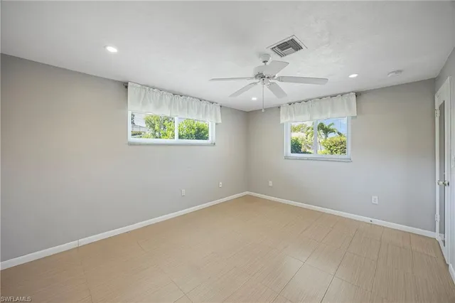 an empty room with windows and ceiling fan