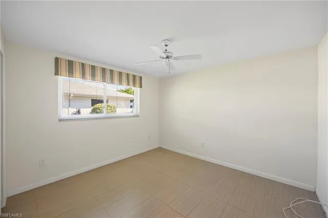 an empty room with windows and ceiling fan