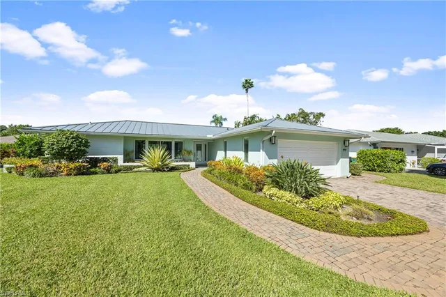 a front view of a house with a yard and potted plants