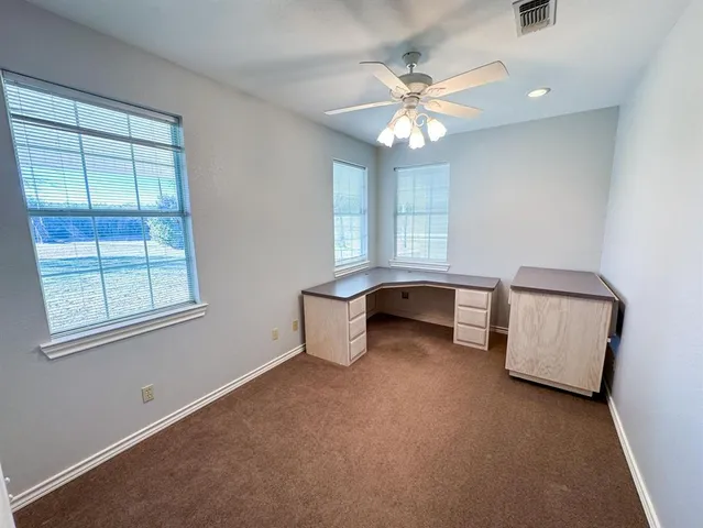an empty room with chandelier fan and windows